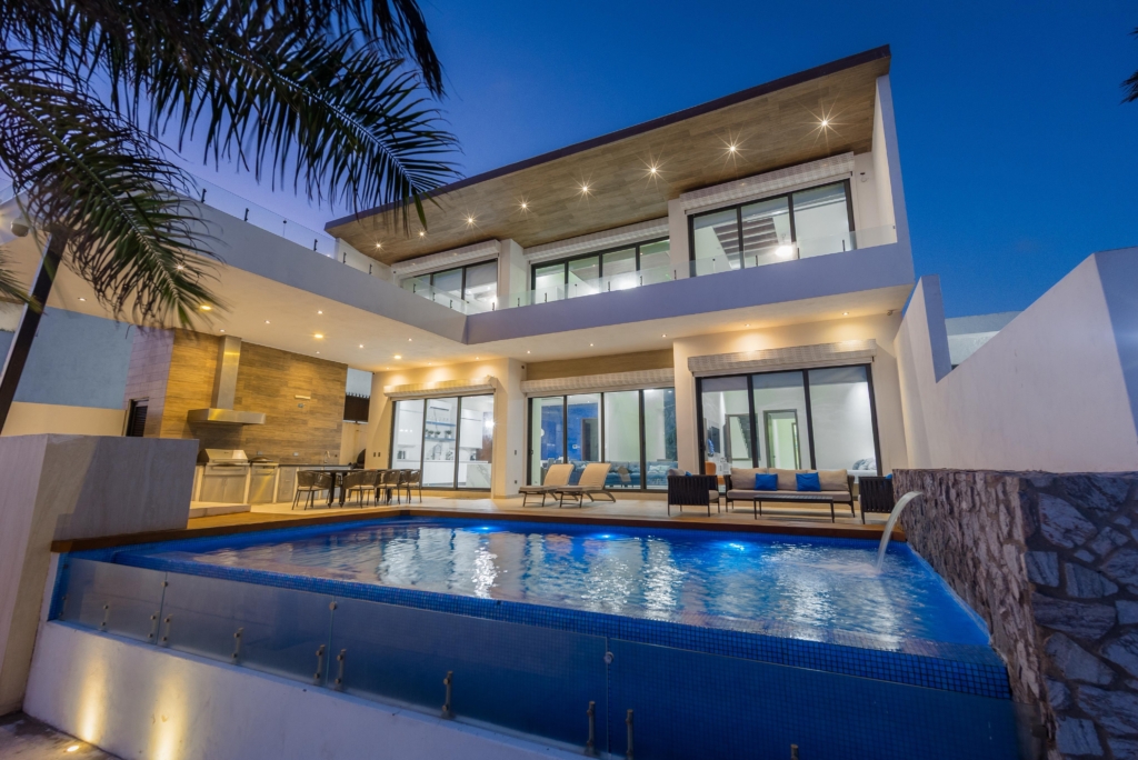 Casa en Kino
Poste 121
Superficie: 568m2
Construcción: 775m2
Hermosa casa frente al mar, completamente equipada y amueblada.
Planta baja:
cochera techada para dos o 3 autos y espacio para lancha, recámara con baño y walking closet con vista al mar, sala doble altura, medio baño, estancia, cocina, alacena y cuarto de lavado. Pasillo de servicio, terraza frente al mar con alberca, asador y firepit. Cuarto de servicio con baño completo.
Planta alta:
Estancia, 2 recámaras con baño, walking closet y terraza con vista al mar. Otra recámara con baño y terraza con vista a la calle principal. Closet de blancos y cuarto de juegos con terraza.
Equipamiento:
- 2 lavadoras, 1 secadora y lavadero.
- lámparas decorativas en toda la casa.
- 8 minisplits en planta alta.
- 4 minisplits en planta baja.
- 5 televisiones en planta alta.
- Cortinas eléctricas.
- Alberca con bomba de calor.
- Jacuzzi en terraza planta alta.
- Madera en paredes.
- Completamente amueblada.
- Cocina con horno, parrilla, microondas y refrigerador de acero inoxidable.
- Cuarzo en superficie de cocina, pared azul y un baño.
- Pisos y paredes de baño de material italiano.
- Interfon, alarma, cámaras hikvision.
- Piedra brasa en ciertos muros.
- Paneles solares, capacidad 20 kilos.
$38 mdp